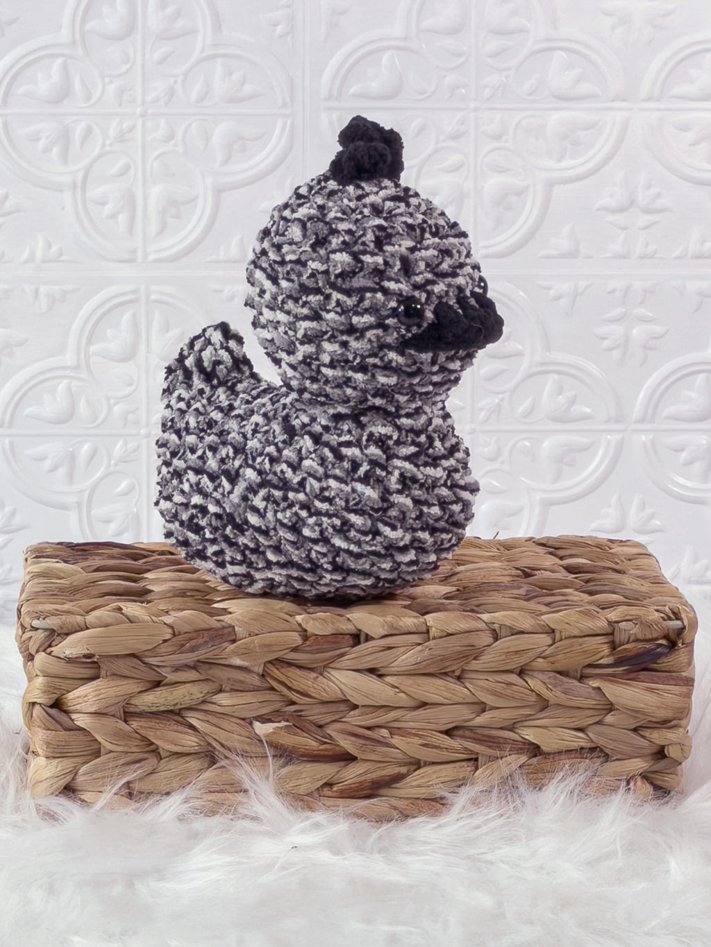 Handmade tweed, black rubber duck crochet plushie shown from an angled view