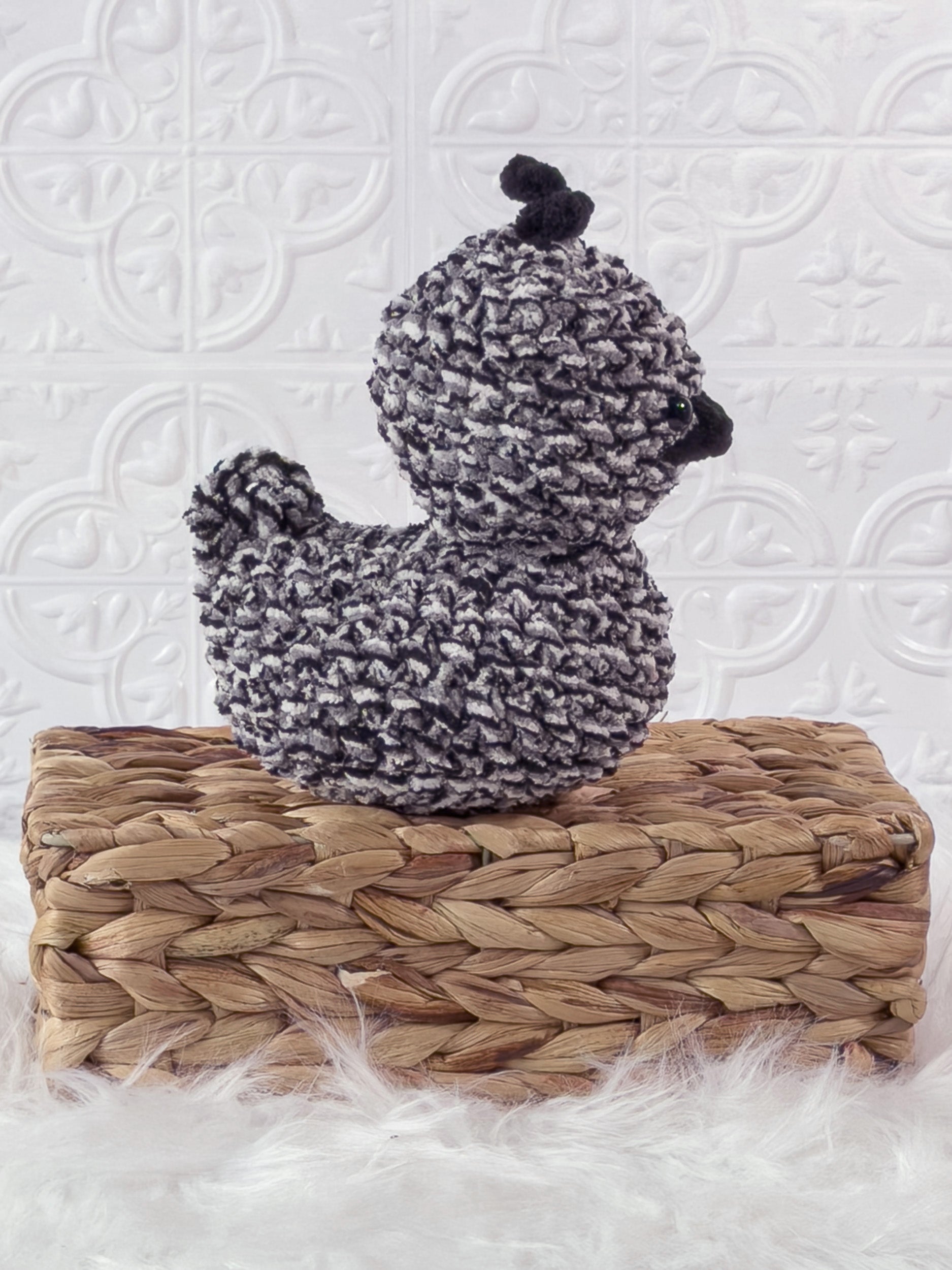 Handmade tweed, black rubber duck crochet plushie shown from the side