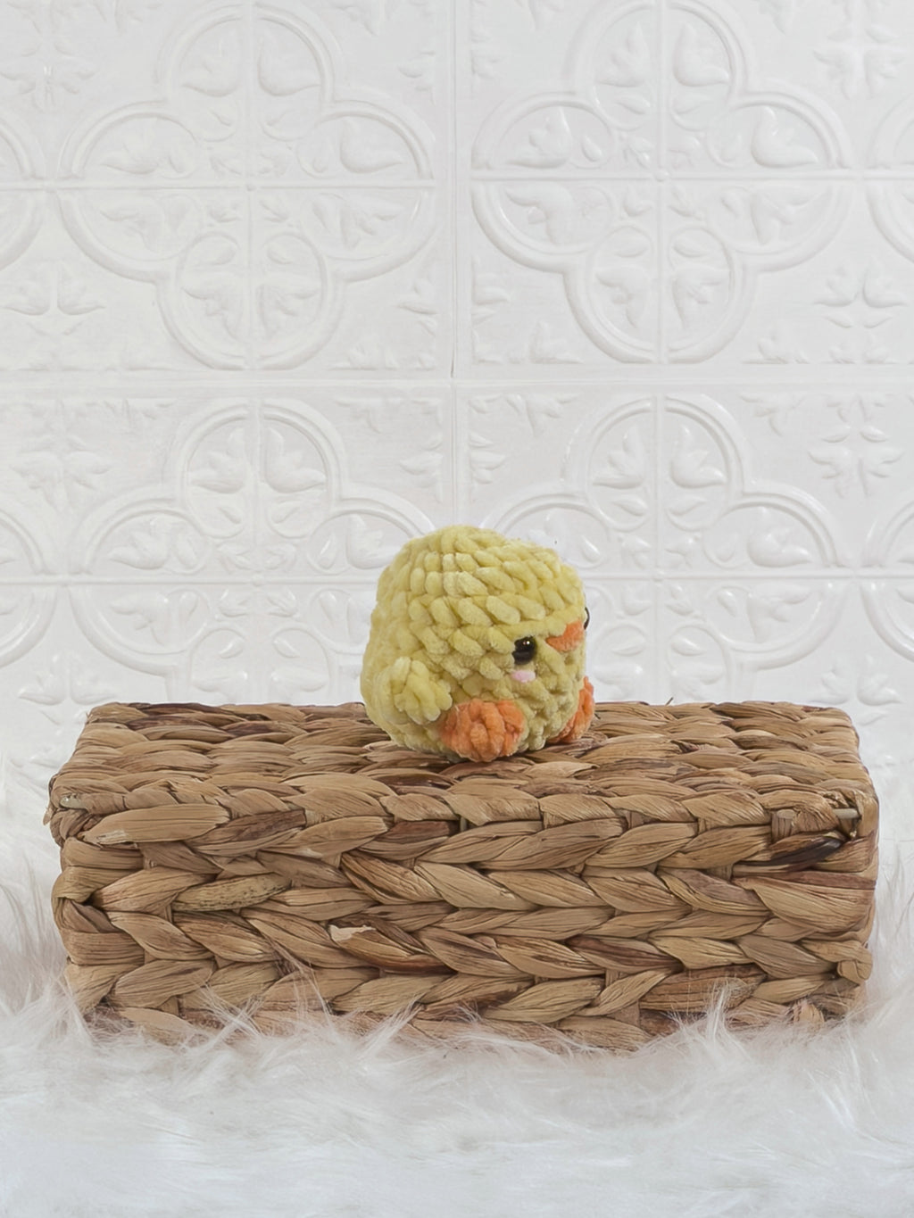 Handmade yellow baby chick crochet plushie shown from an angled view