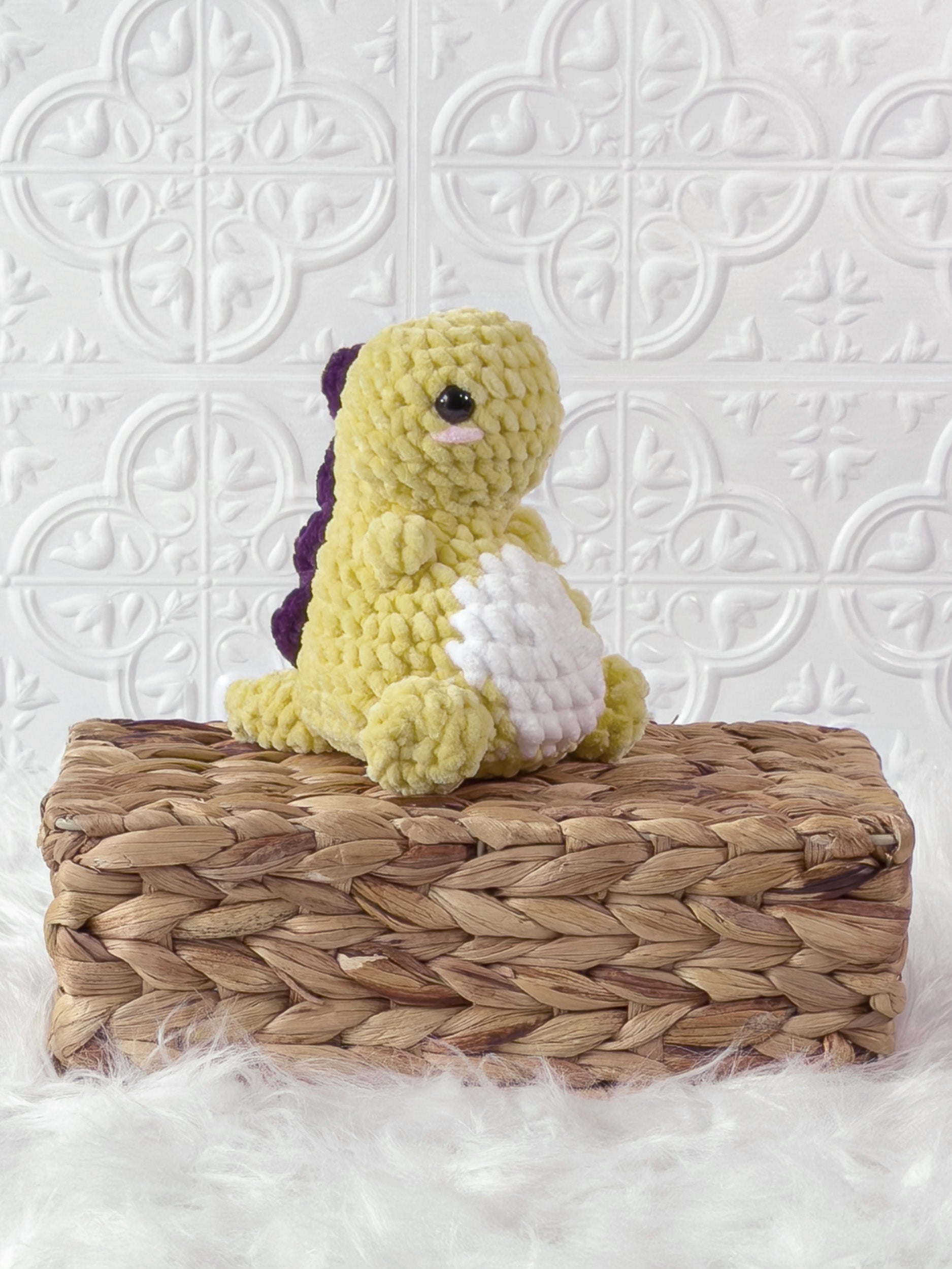 Handmade yellow chunky dino crochet plushie shown from an angled view